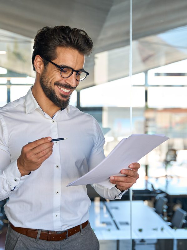 Happy young Latin business man checking financial documents in office.